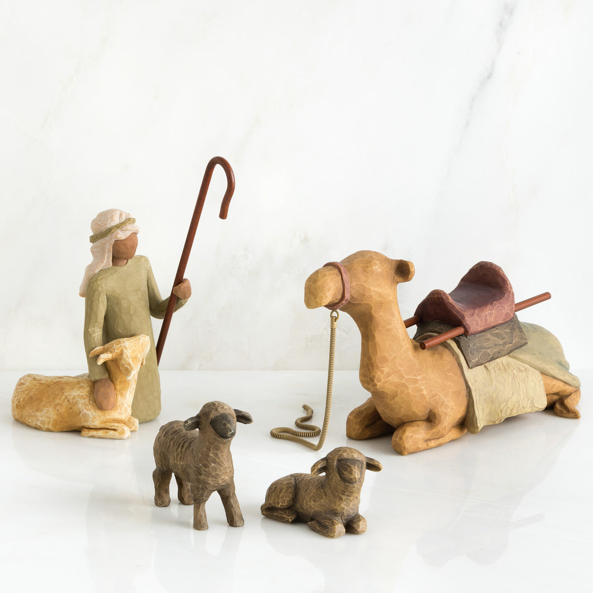 Set of figurines - golden camel laying down surrounded by two grey sheep and wiseman petting golden lamb