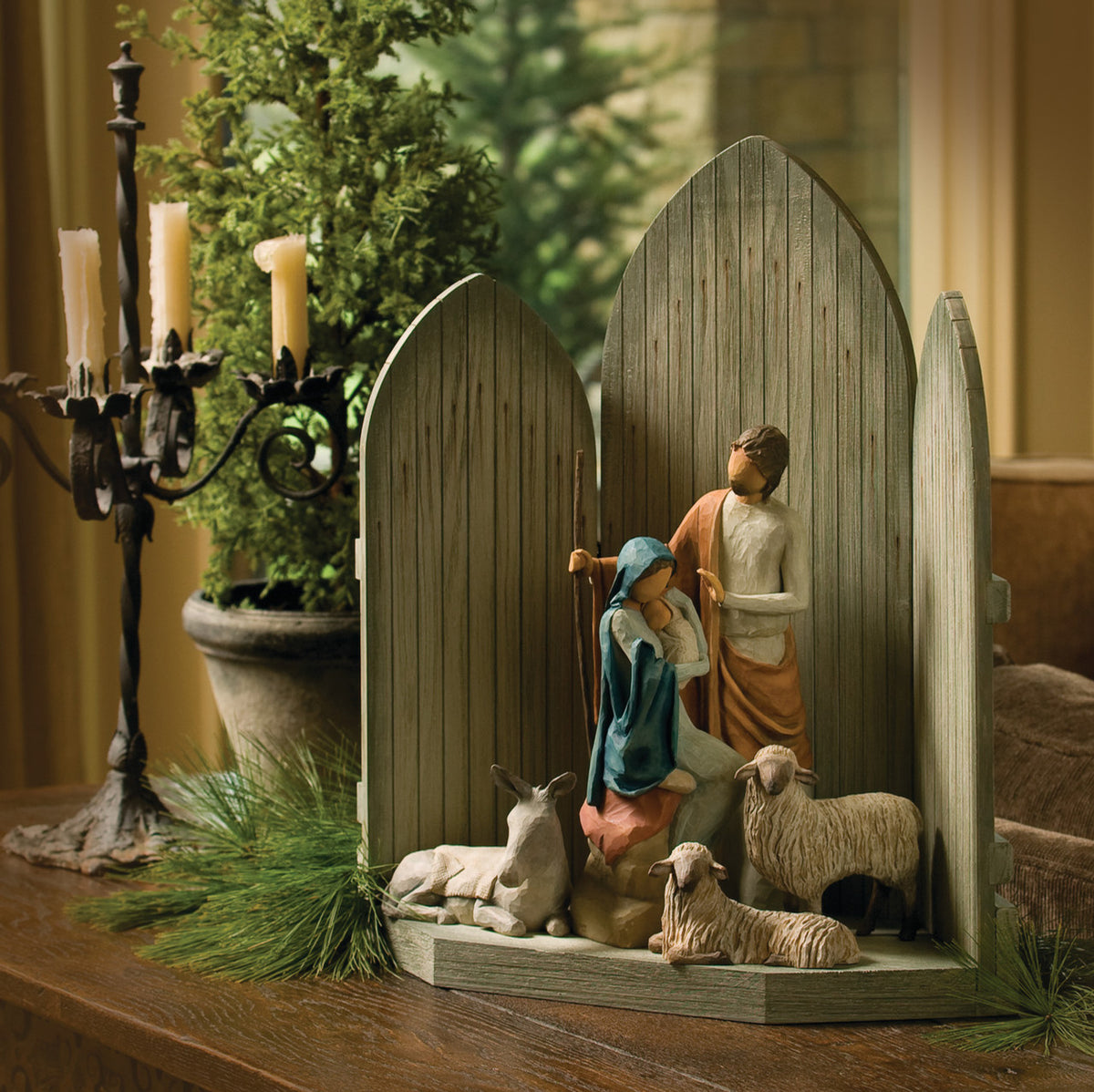 Side view of dark grey barn tri-fold on table with mary and joesph figurines in the center with two white sheep and donkey figurine under them