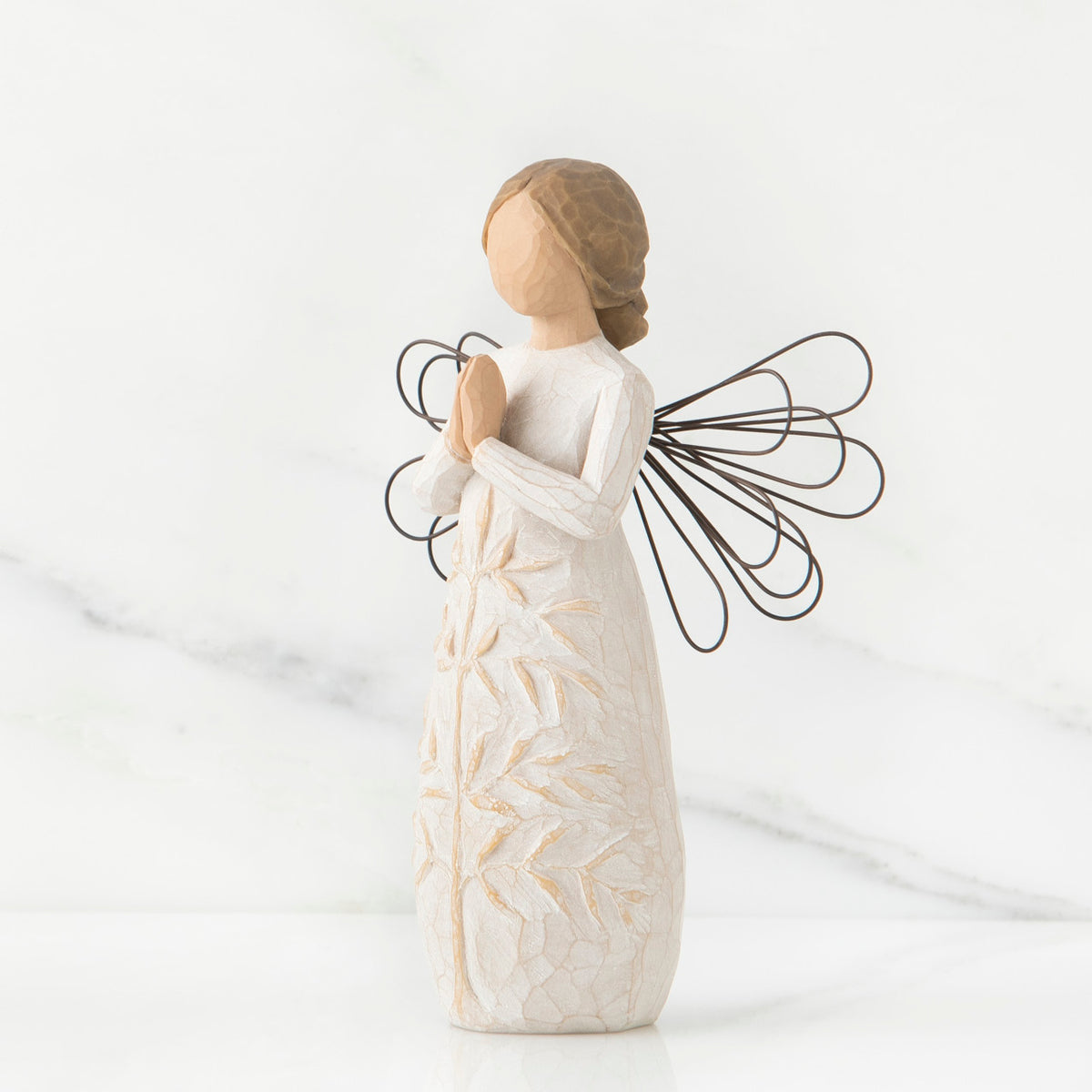 Side view of brunette angel figurine in white dress holding hands in prayer with black wire wings